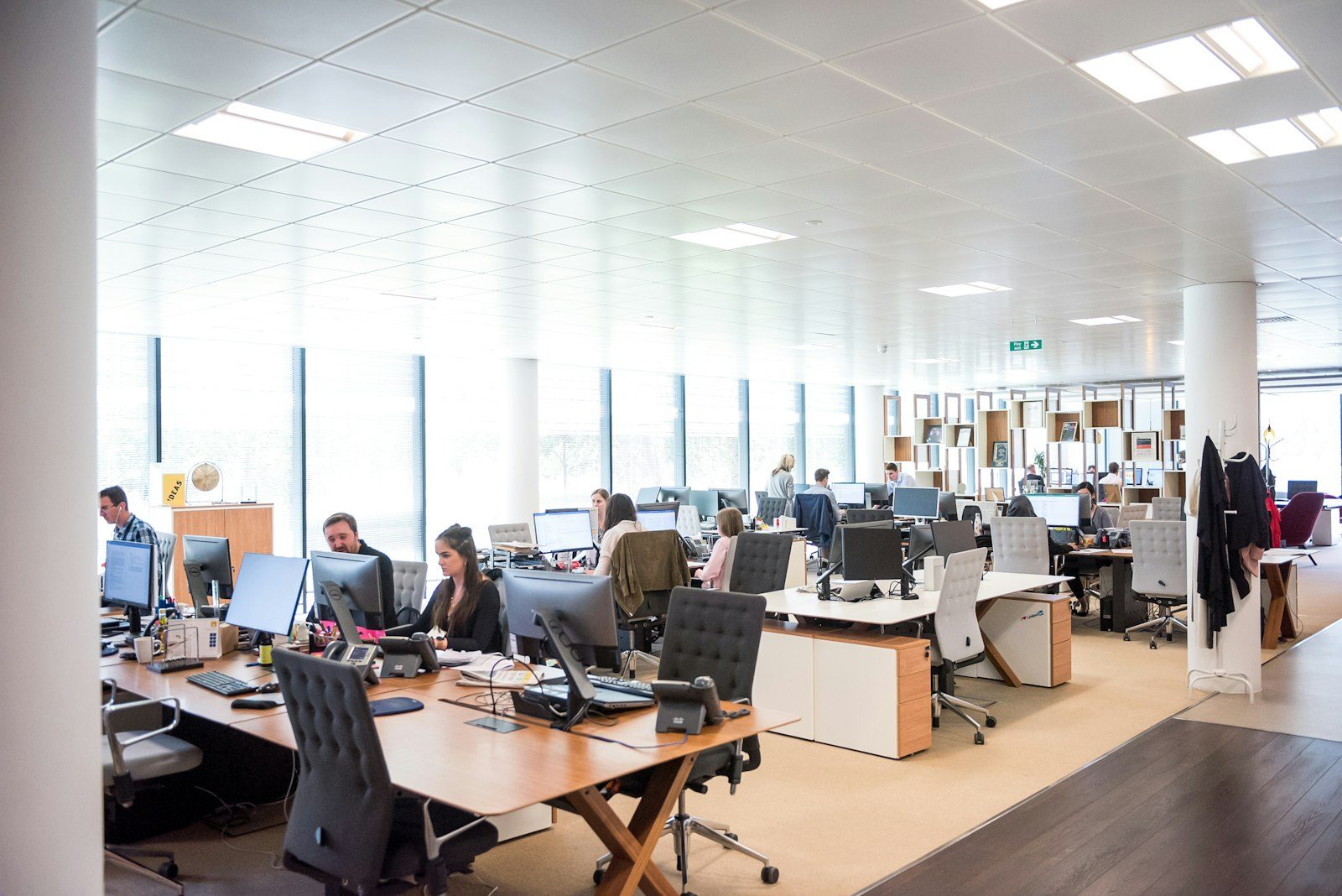 Virtual receptionist vs answering service comparison Open-plan office with staff answering desk phones, the work virtual receptionists and answering services take over