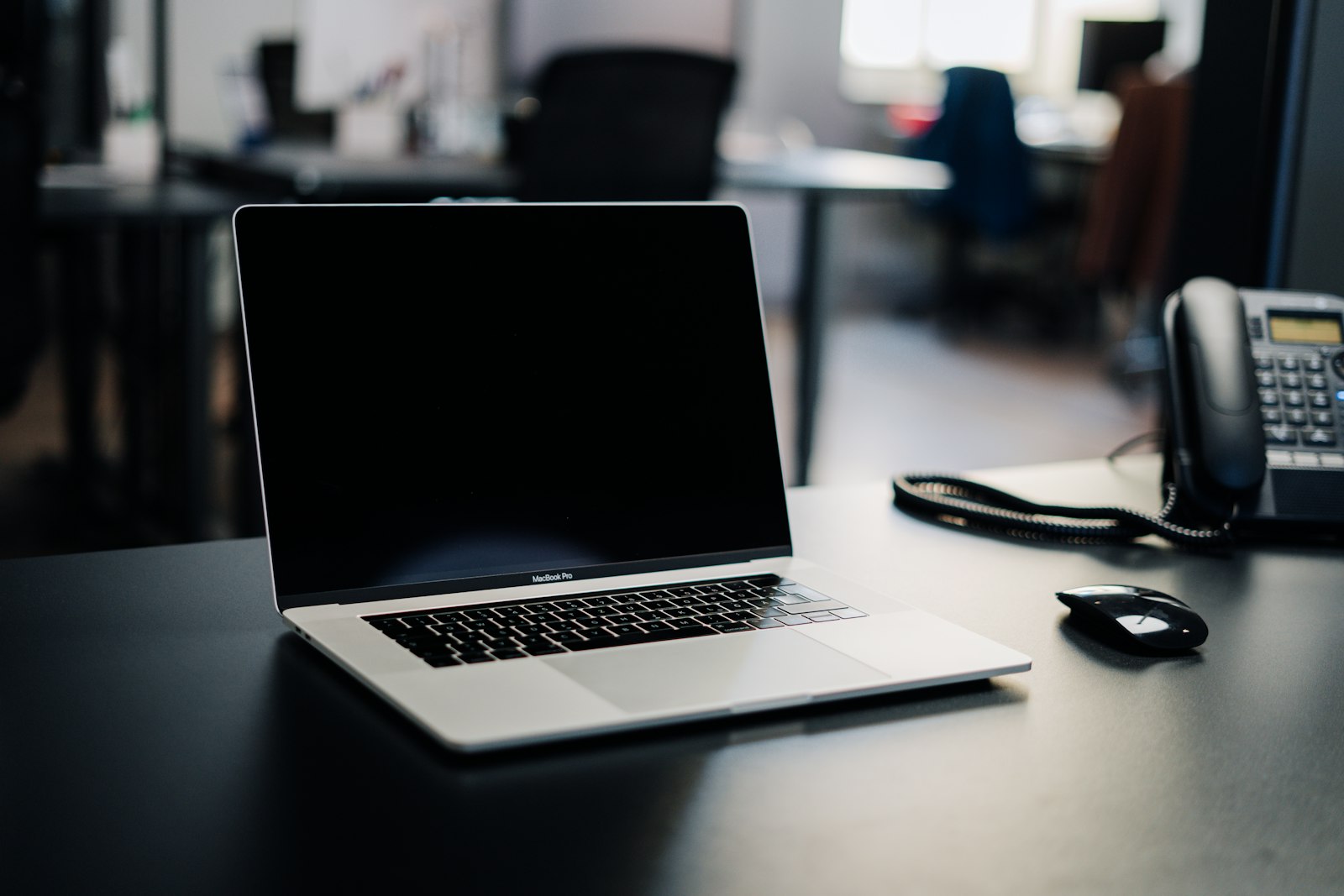 Office desk phone beside a laptop, the hardware an automated phone answering system replaces
