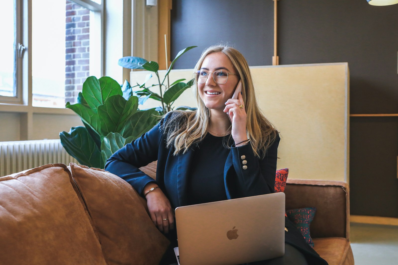 Professional receptionist answering a business phone call with a laptop open in front of her
